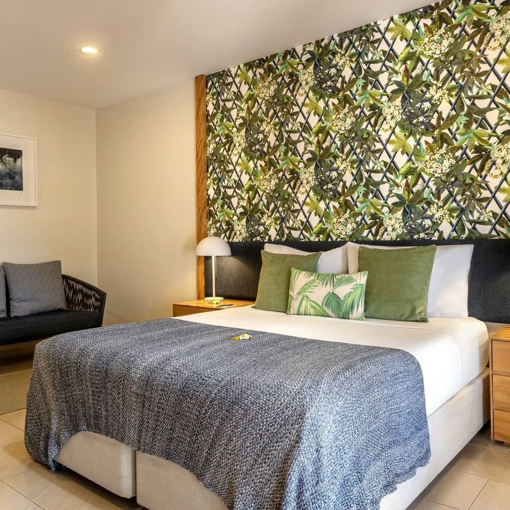 Decorative floral wall with large bed beside small sofa in Lagoon Superior Room at warwick le lagon-vanuatu