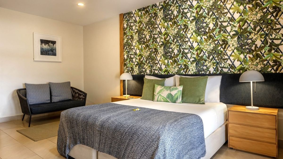 Decorative floral wall with large bed beside small sofa in Lagoon Superior Room at warwick le lagon-vanuatu
