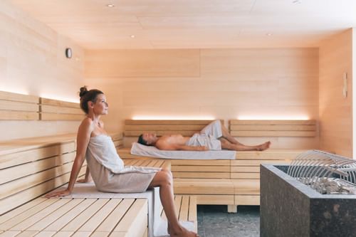 A man & a woman relaxing in a sauna at Hotel Liebes Rot Flueh