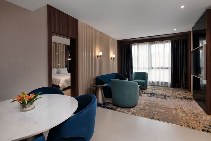 TV lounge with plush sofa and dining table by the window in Junior Suite at Warwick Al Taif Hotel