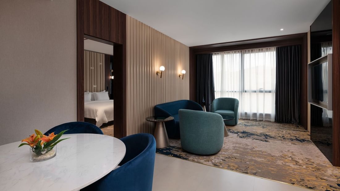 TV lounge with plush sofa and dining table by the window in Junior Suite at Warwick Al Taif Hotel