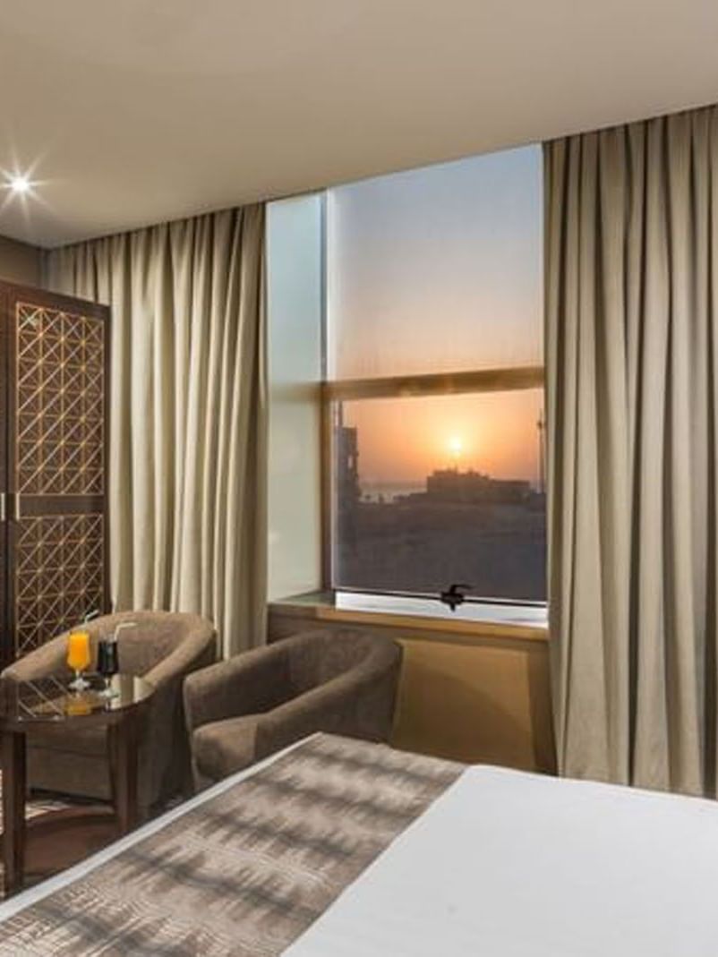 Double bed by a patterned headboard under warm spotlights in Deluxe King Sea View / Twin t Naviti by Warwick Al Khobar