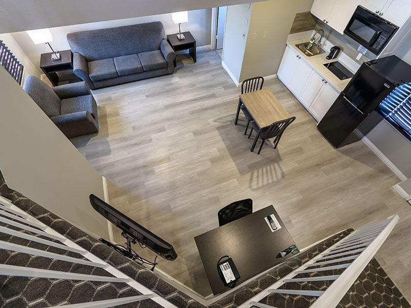A wide-angle view of a suite's living area, kitchen, and staircase from above.