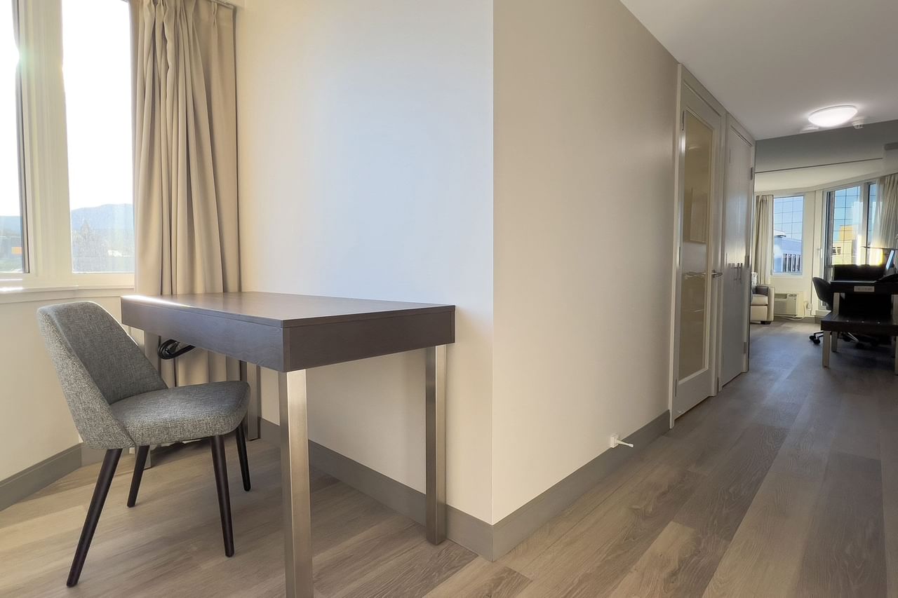 Hotel guestroom with desk, chair and hallway to guest room