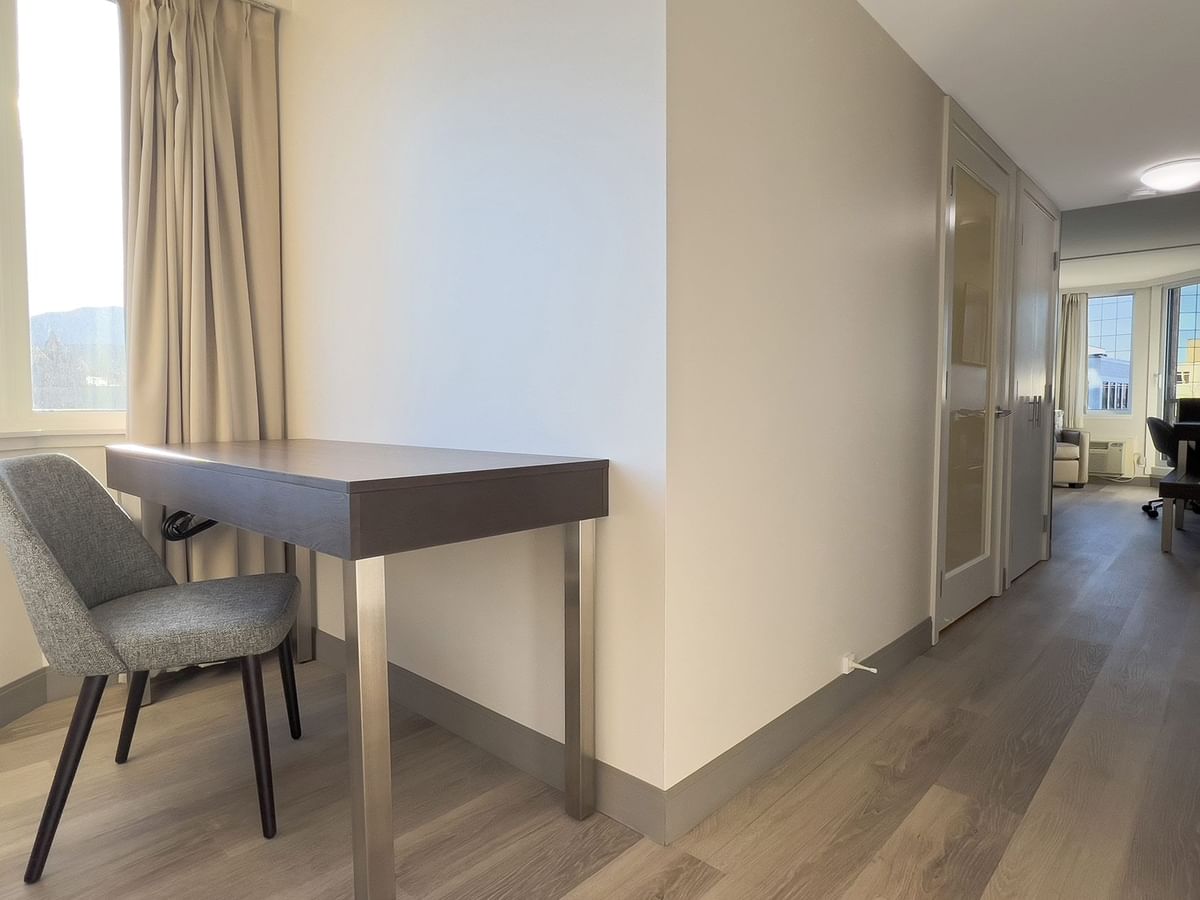 Hotel guestroom with desk, chair and hallway to guestroom