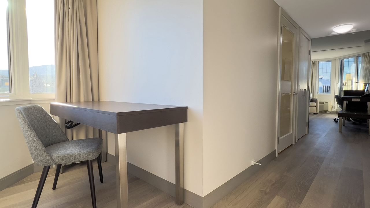 Hotel guestroom with desk, chair and hallway to guestroom