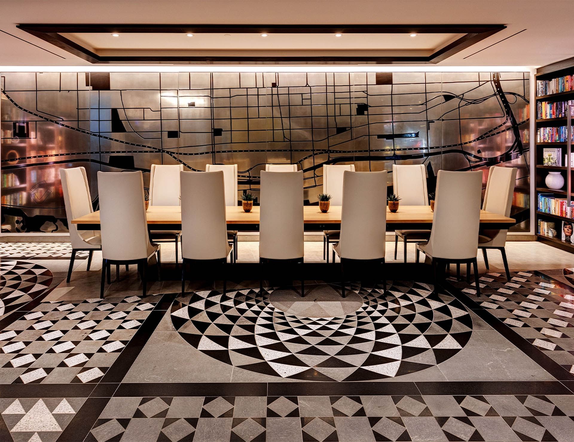 Elegant boardroom table and high-back chairs facing a geometric floor and map wall design at Hotel X Toronto