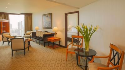 Living area with plush seating, a coffee table, & windows offering city views in Olimpo Suite at Hotel Los Delfines & Casino