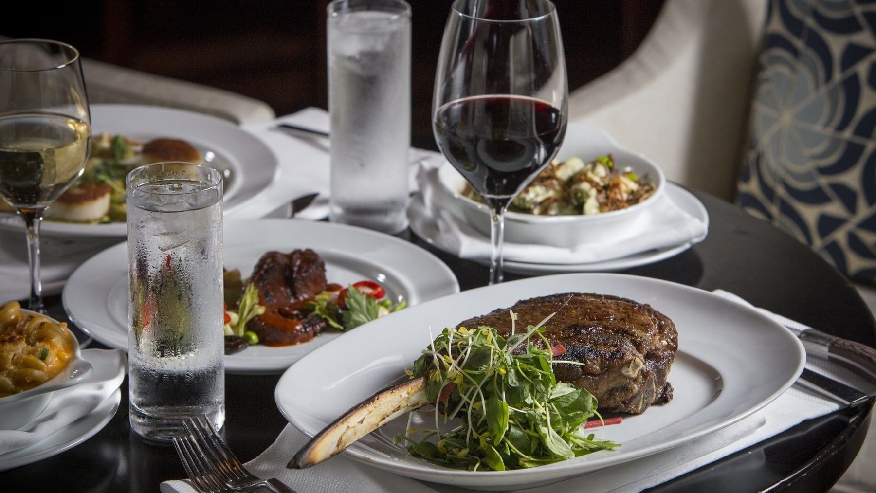 A table adorned with plates of delicious food & glasses of wine at The Diplomat Resort