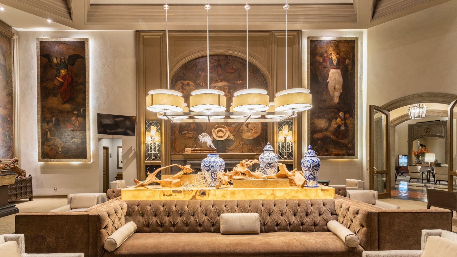 Elegant Los Murales bar featuring tufted sofa decorated with blue ceramic vases and warm lighting at Quinta Real Monterrey