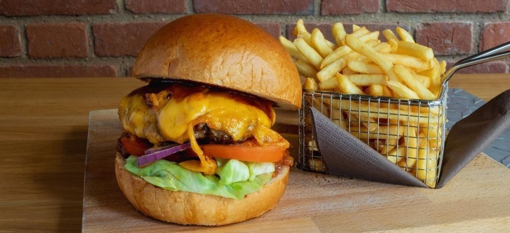 Cheeseburger and fries on wooden board