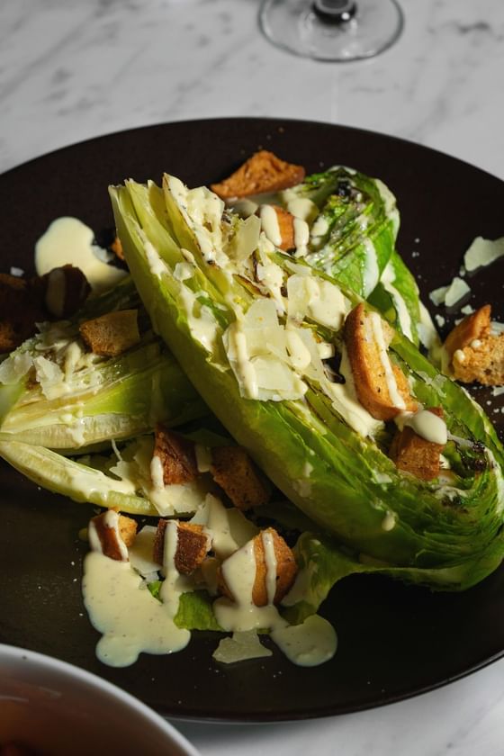 Grilled romaine lettuce topped with Caesar dressing, croutons, and shaved Parmesan served at Cypress & Oak