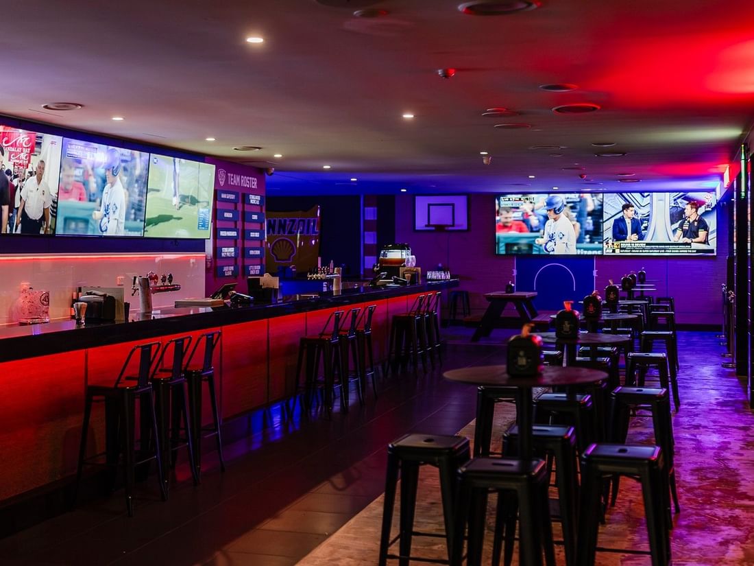 Vibrant KG Sport Bar featuring TV screens & tables with red neon lighting at Mercure Brisbane King George Square