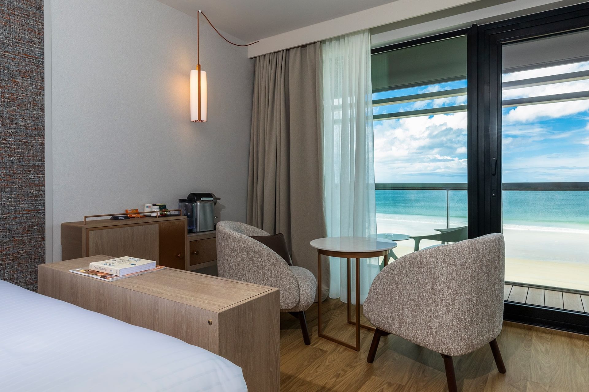 Intérieur et décoration d'une chambre avec coin salon et vue sur l'océan à l'Oceania Saint-Malo