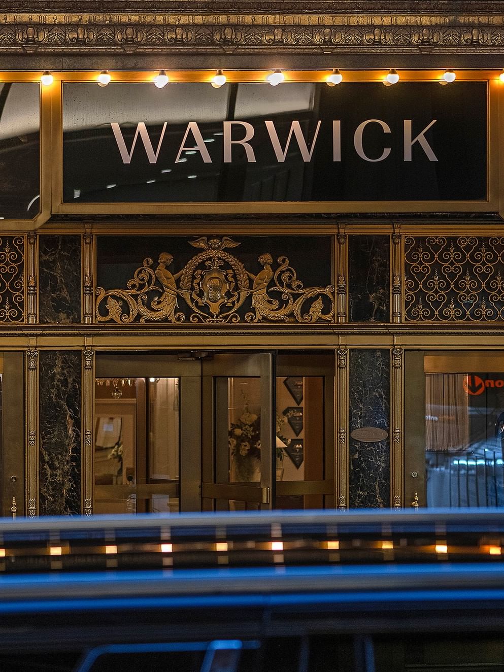 Entrance to Warwick New York hotel with car passing in front