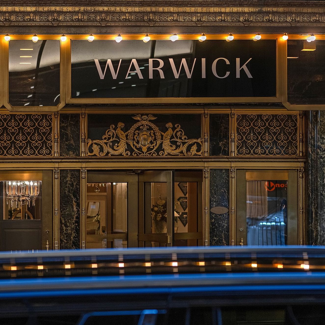 Entrée de l'hôtel Warwick New York, avec une voiture qui passe devant.