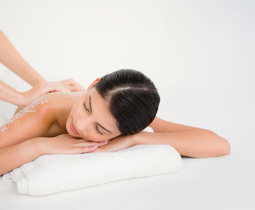 Smiling woman enjoying a relaxing salt scrub treatment and massage at the beautiful Peppers Seminyak spa