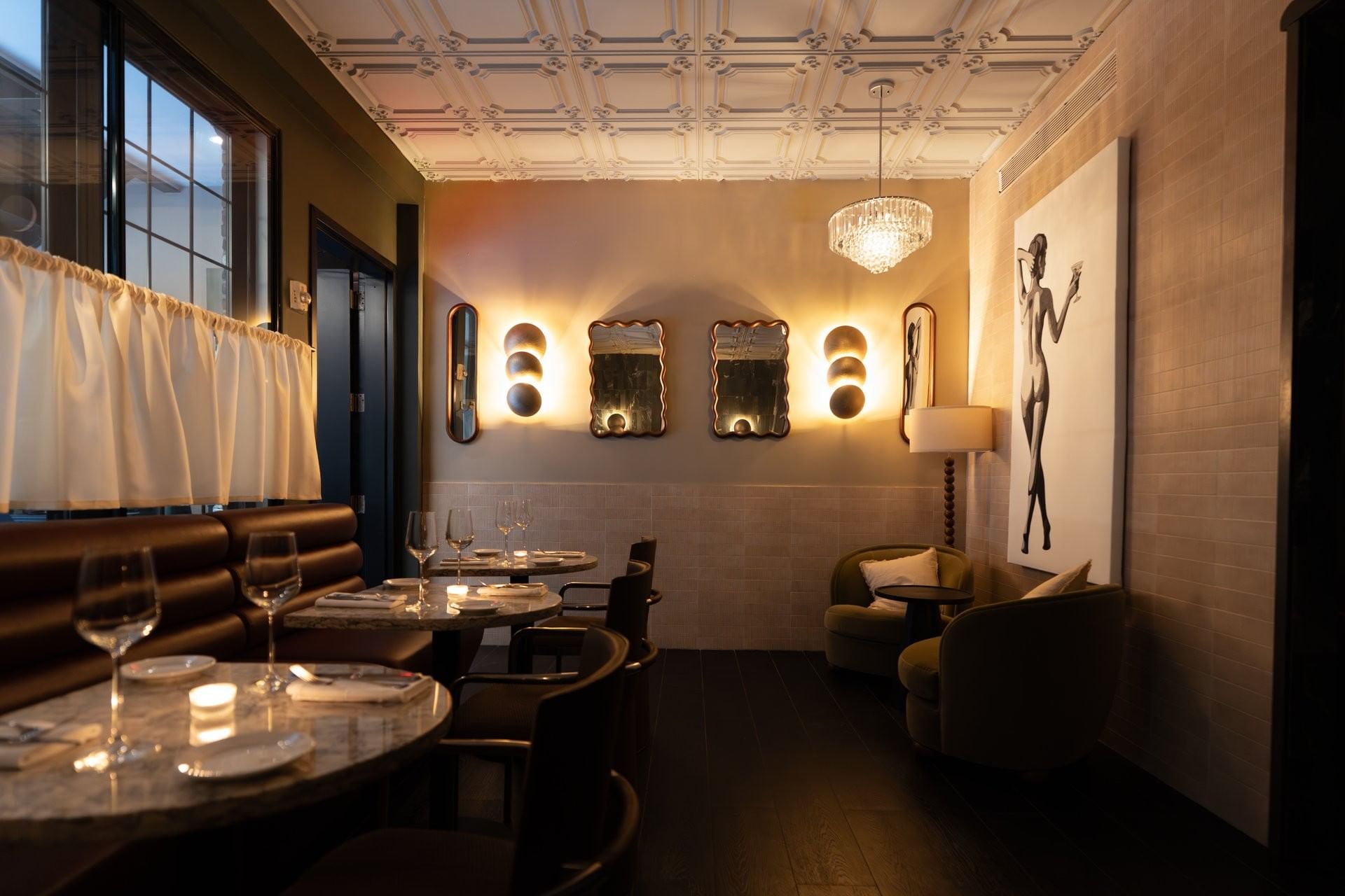 A dimly lit dining area with booth seating and tables set for dinner.