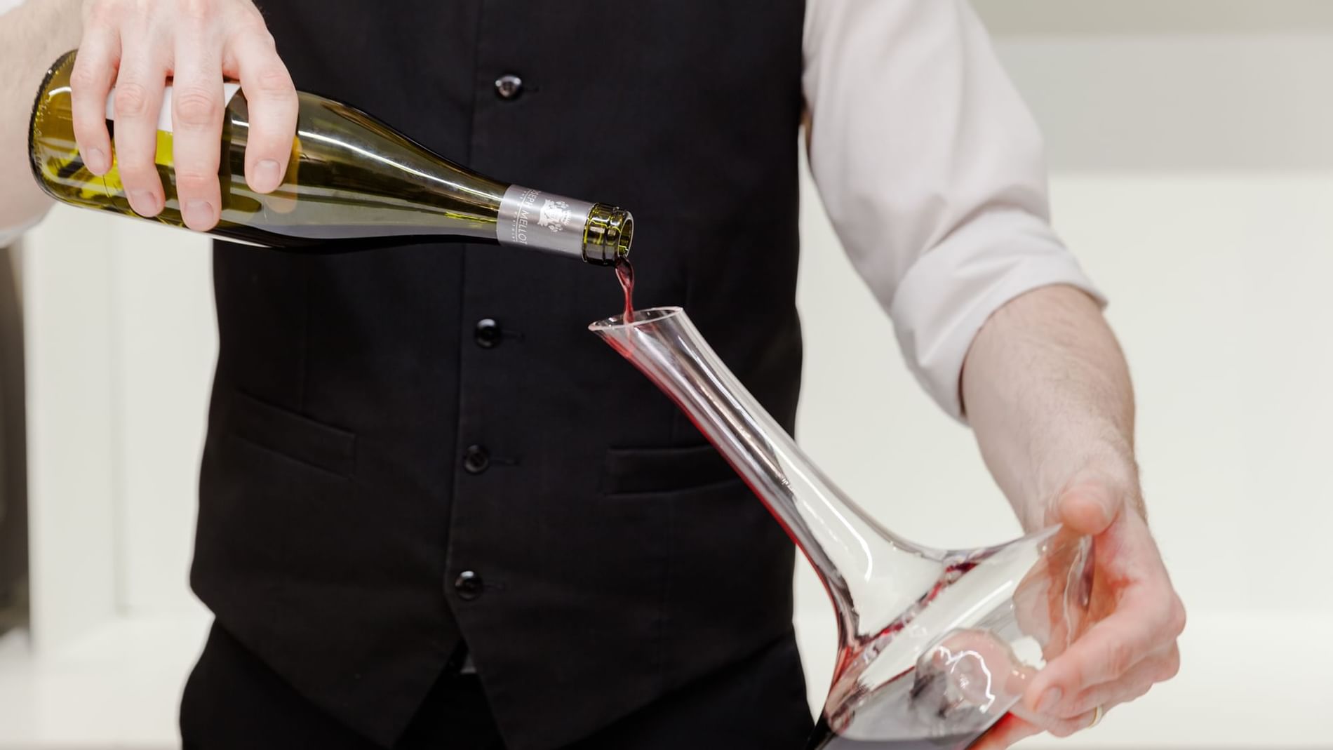 A waiter pouring wine in Le Carre Gourmand at Originals Hotels