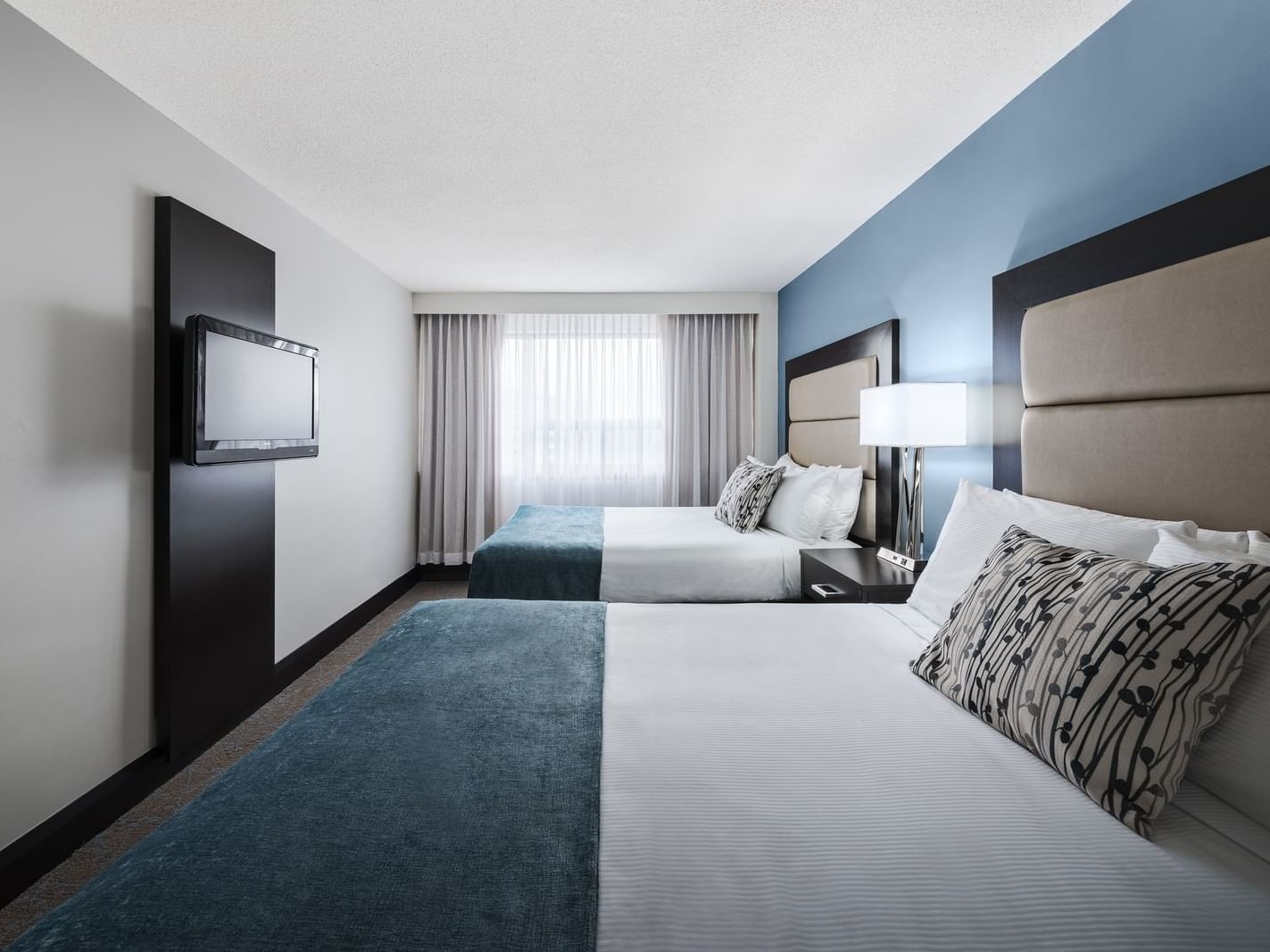 room with two beds and television on wall