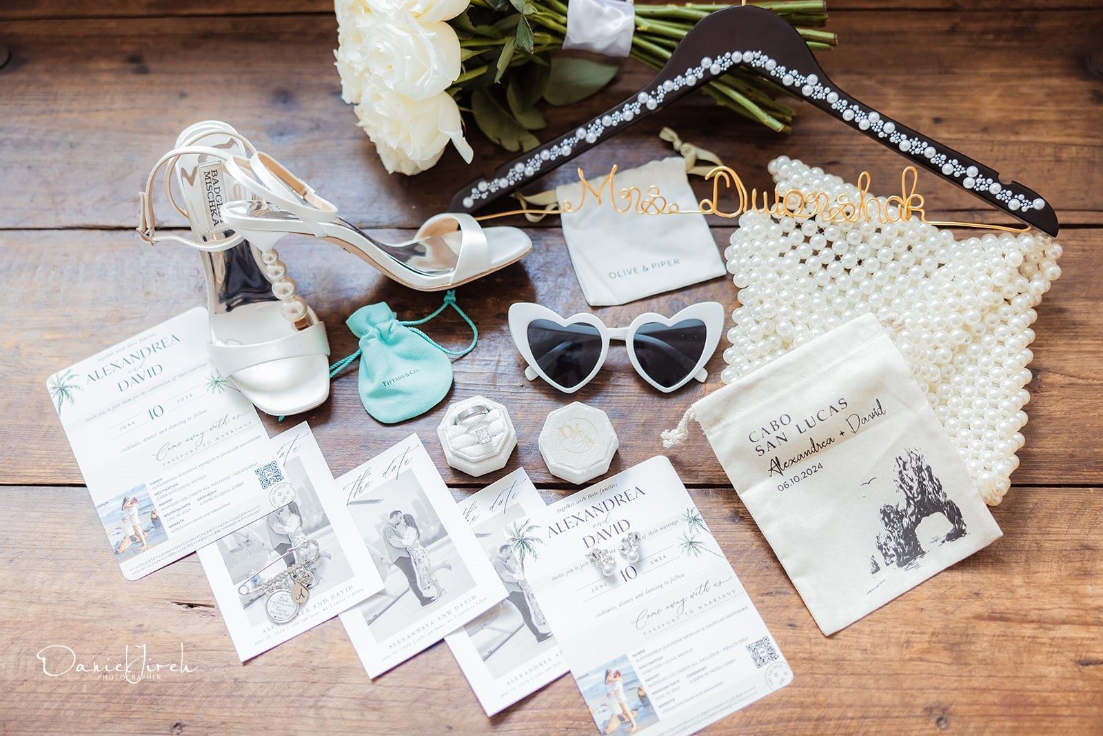 Wedding flat lay with heels, heart sunglasses, invites, and a pearl bag at Marquis Los Cabos Resort