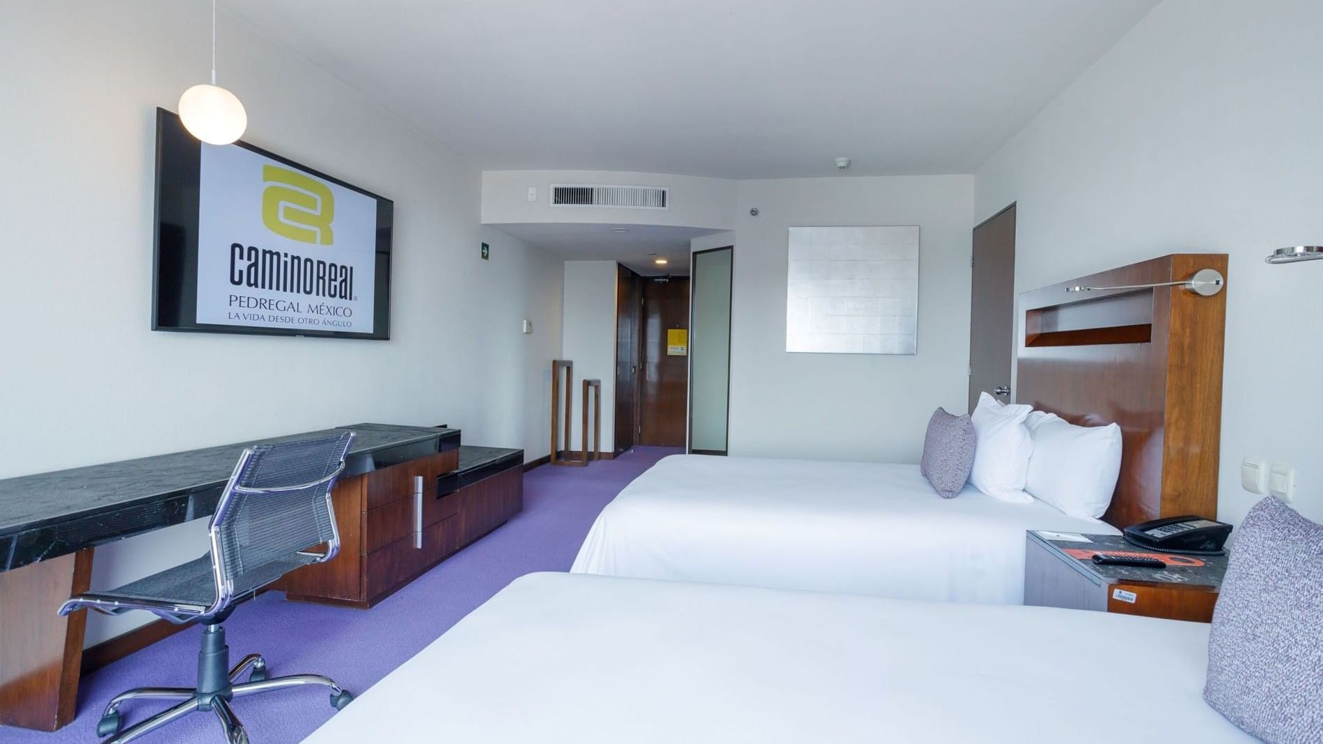 2 Double Camino Real Club with clean white linens, a work desk, and purple carpeting at Camino Real Pedregal Mexico