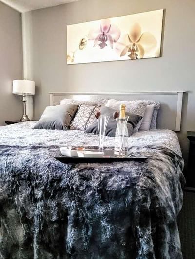 Cozy bed with a fur blanket & two glasses placed on it in Romantic Spa Suite at Service Plus Inns & Suites Drayton Valley