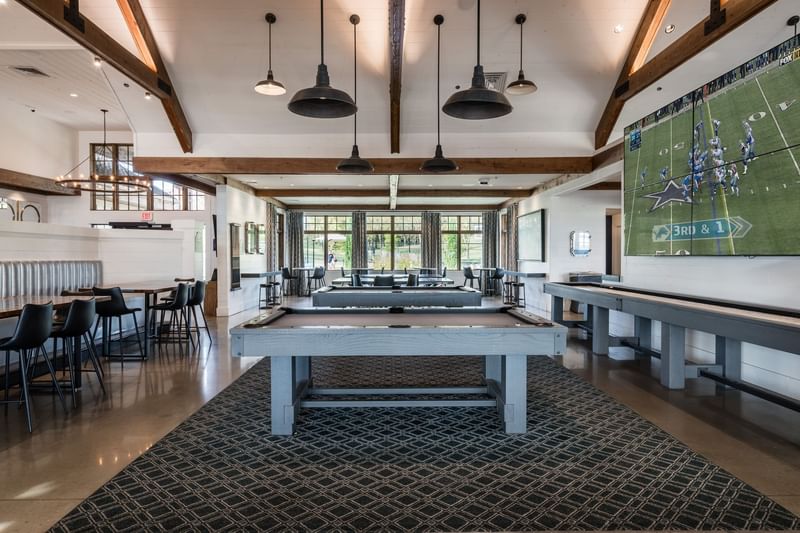 Spacious clubhouse interior with pool tables, shuffleboard, and a large TV at Shangri-La Monkey Island