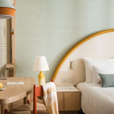 A hotel room with a round bed, wooden desk, patterned wall, and hanging lamp.
