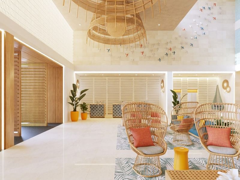 Espacioso lobby en Fiesta Americana Funeeq Punta Cana con sillas de mimbre tipo pavo real y techos altos arquitectónicos
