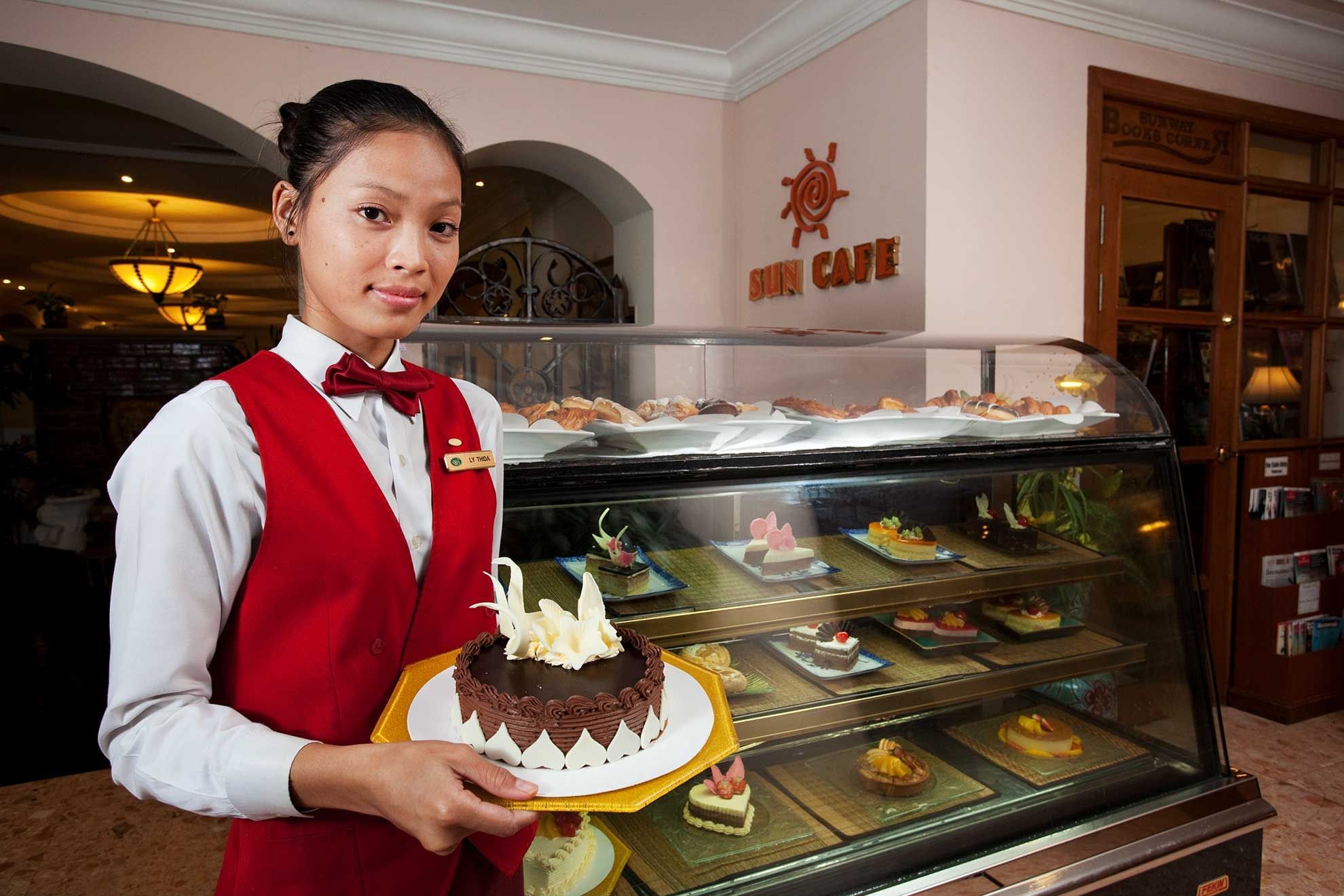 Hotel staff holding a Birthday cake by the counter at Sunway Hotel Phnom Penh