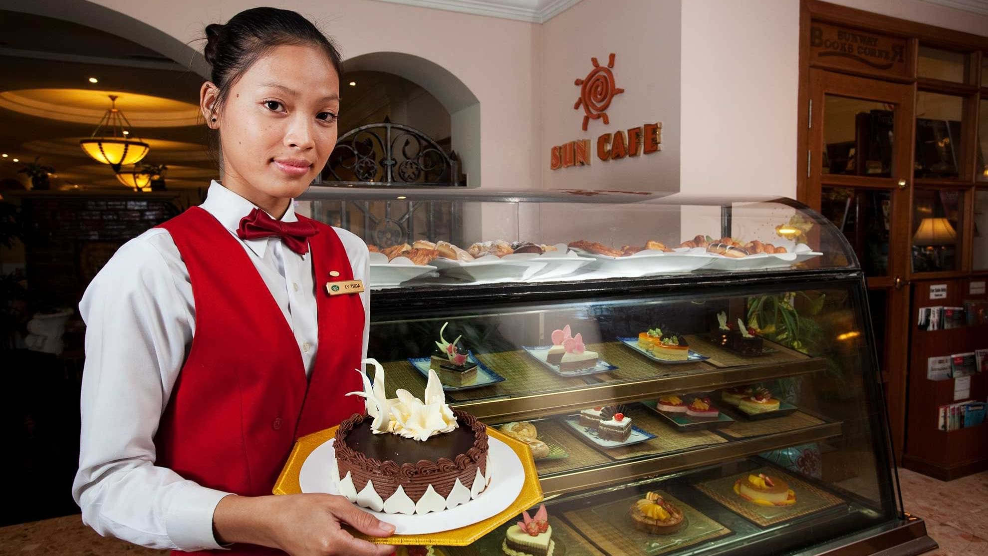 Hotel staff holding a Birthday cake by the counter at Sunway Hotel Phnom Penh