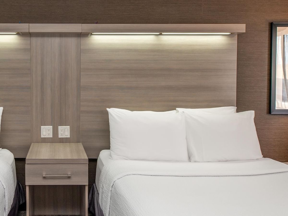 Coast Premium Two Queens room with crisp white bedding and modern wood accents at Coast Calgary University Area Hotel by APA