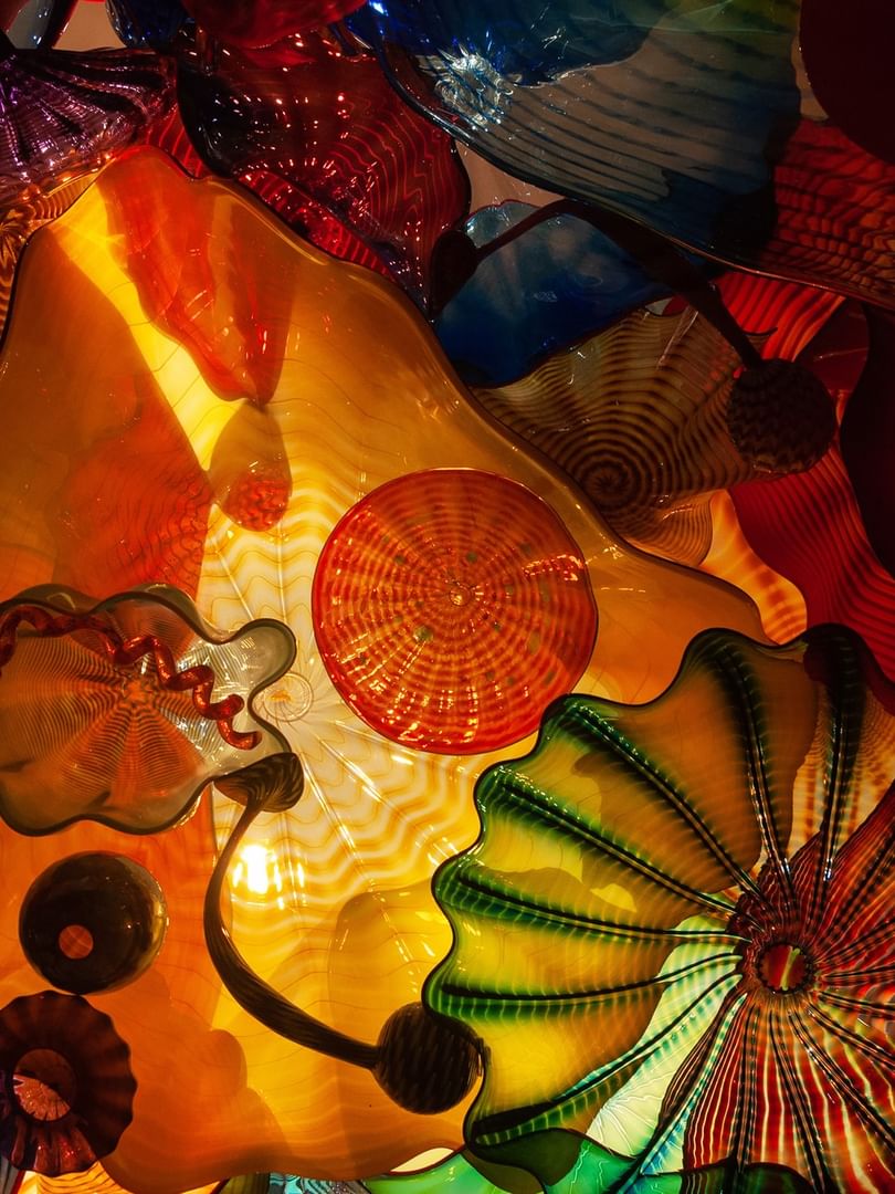 Vibrant glass sculptures featuring orange and green wavy patterns under bright lights at Warwick Seattle