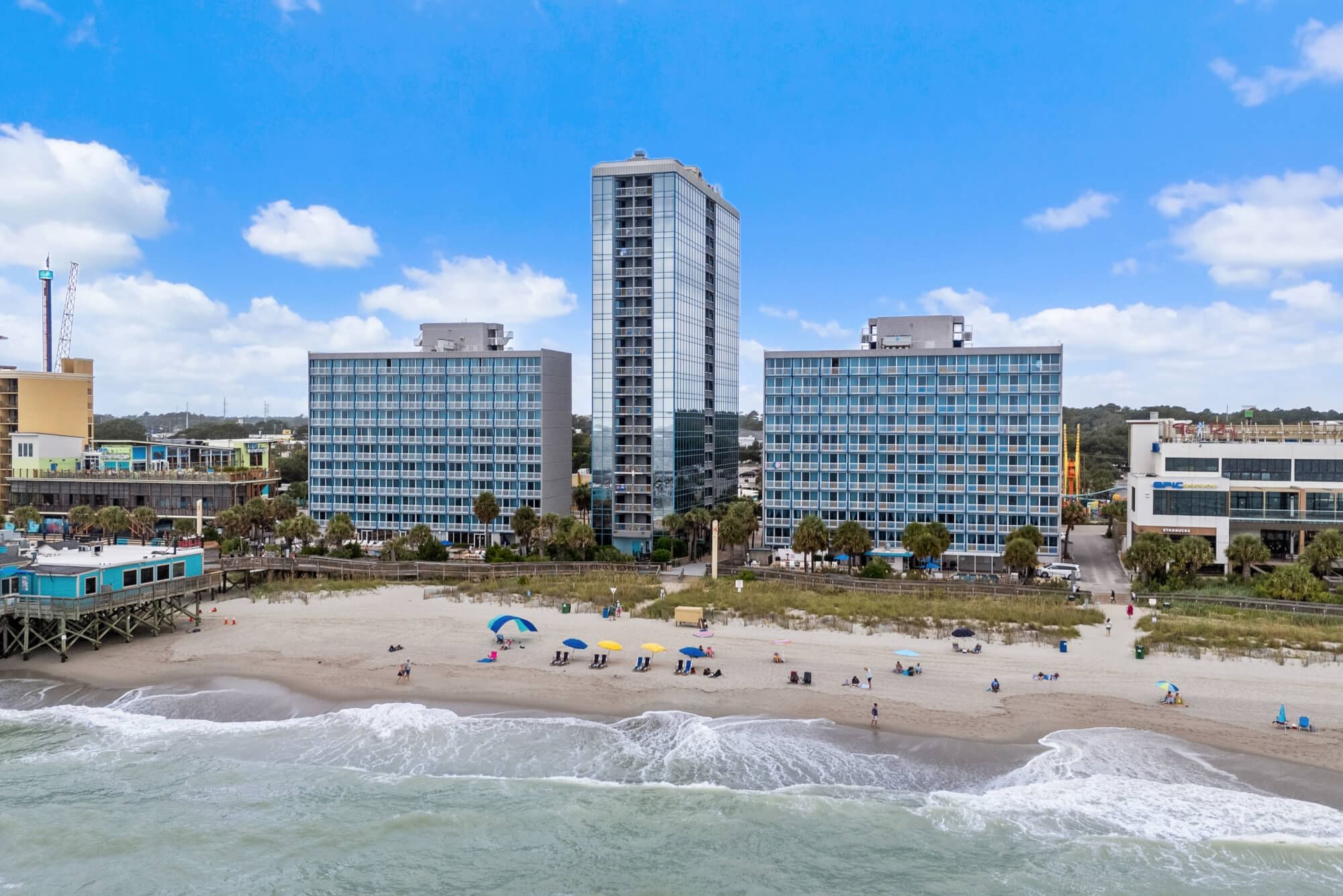 A beachfront hotel with multiple buildings and a sandy beach.