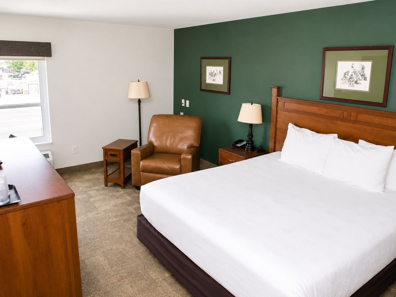 Executive King room with king bed, brown leather chair, wooden furniture, and green accent wall at - Boothill Inn