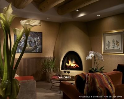 Cozy corner in Executive Lounge at Hilton Santa Fe Buffalo Thunder with a glowing fireplace, artwork, and fresh flowers
