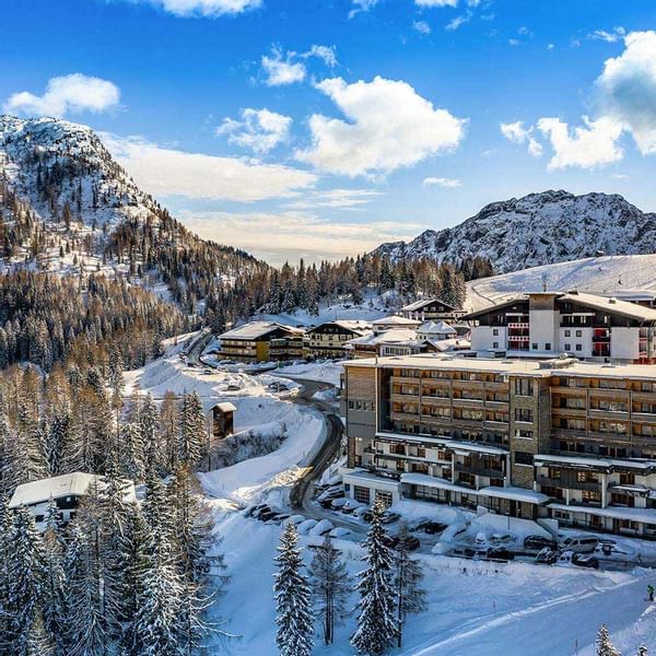 Exterior view of snow-covered Falkensteiner Hotel Cristallo with mountain backdrop