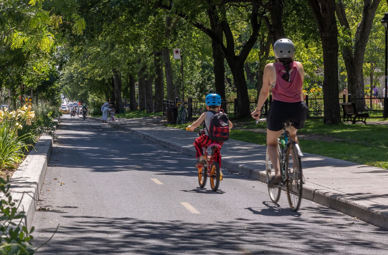 Cycliste et enfant sur piste cyclable bordée d'arbres et de fleurs à Warwick Le Crystal Montreal