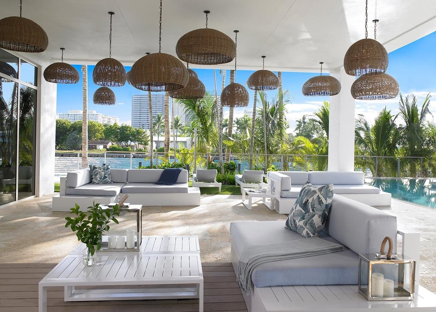 A poolside seating area with wicker light fixtures and a water view.