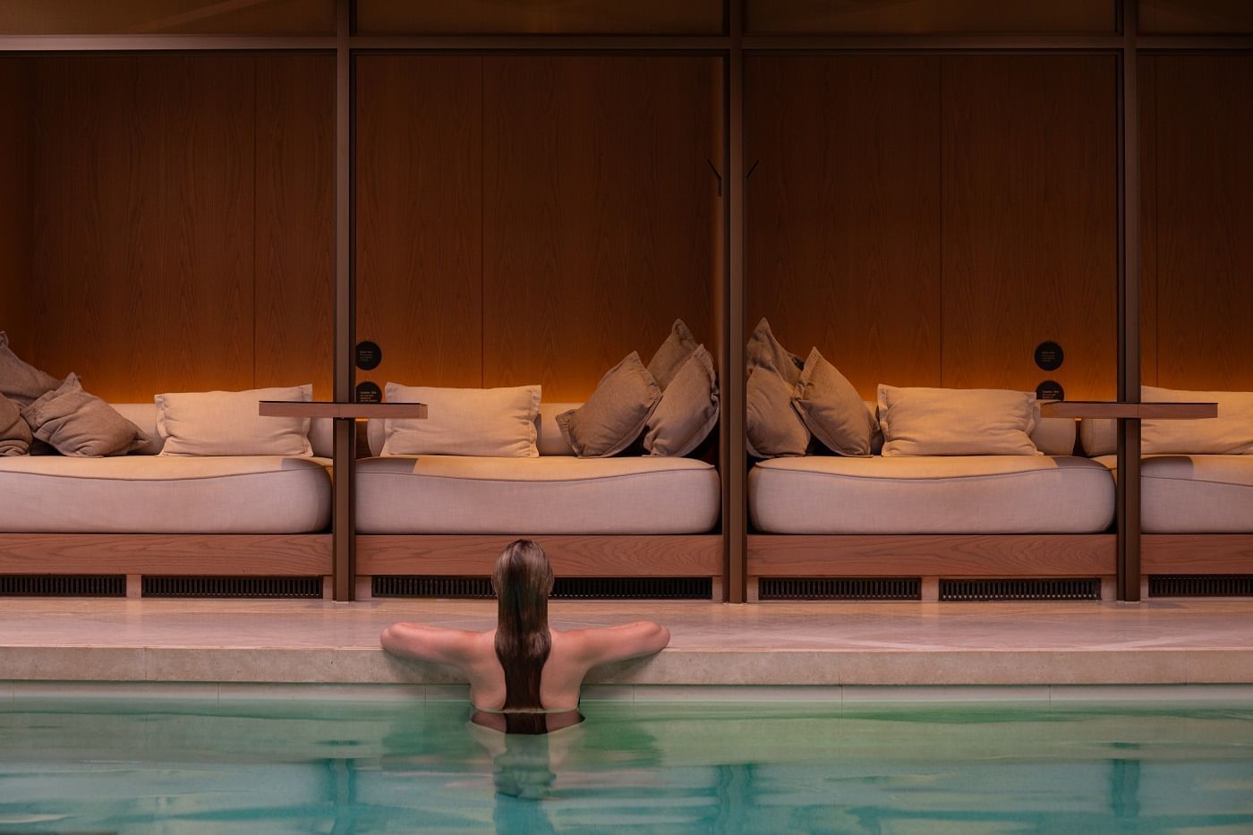 Woman relaxing in a hotel pool area with lounge beds at The Londoner Hotel