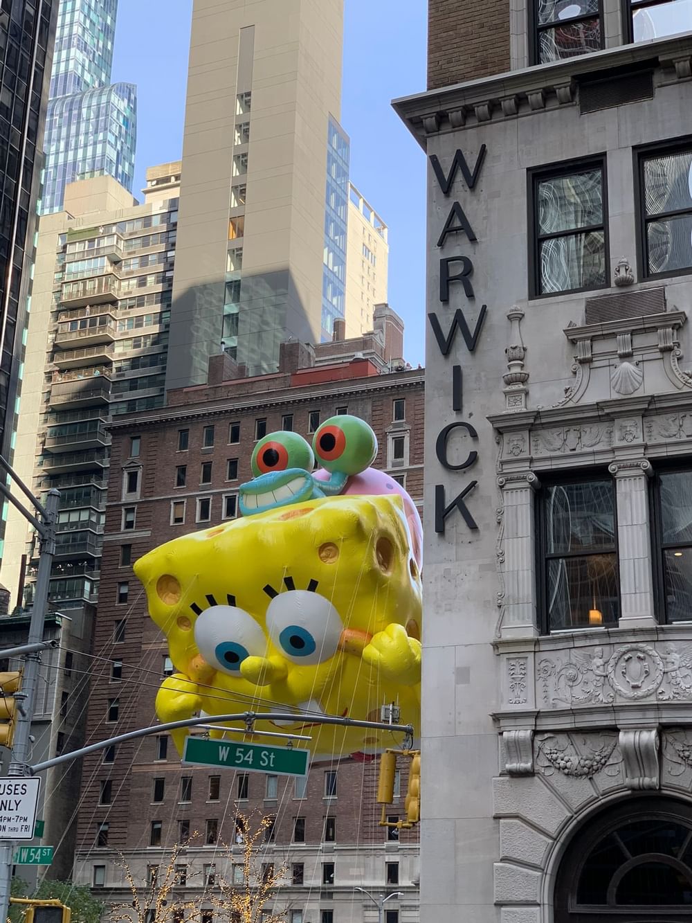 Giant SpongeBob SquarePants balloon floats past city buildings during a parade of Warwick Hotels and Resorts