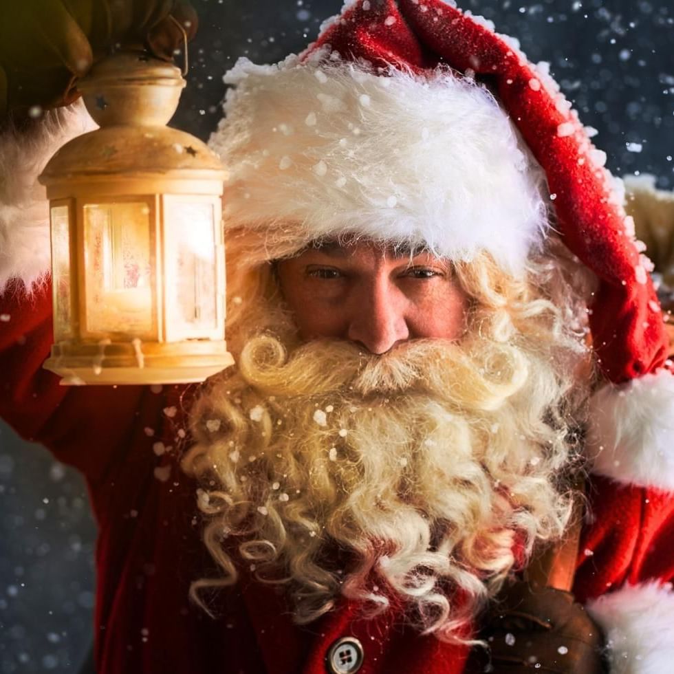 Santa Claus holding lamp in snow