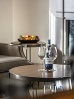 Wine and glasses on a wooden table by a grey armchair near a fireplace in Balcony Junior Suite at Warwick San Francisco