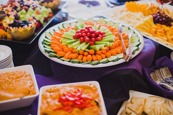 Large platter of mixed vegetables with bowls of dipping sauce on a purple cloth display at Oregon Garden Resort