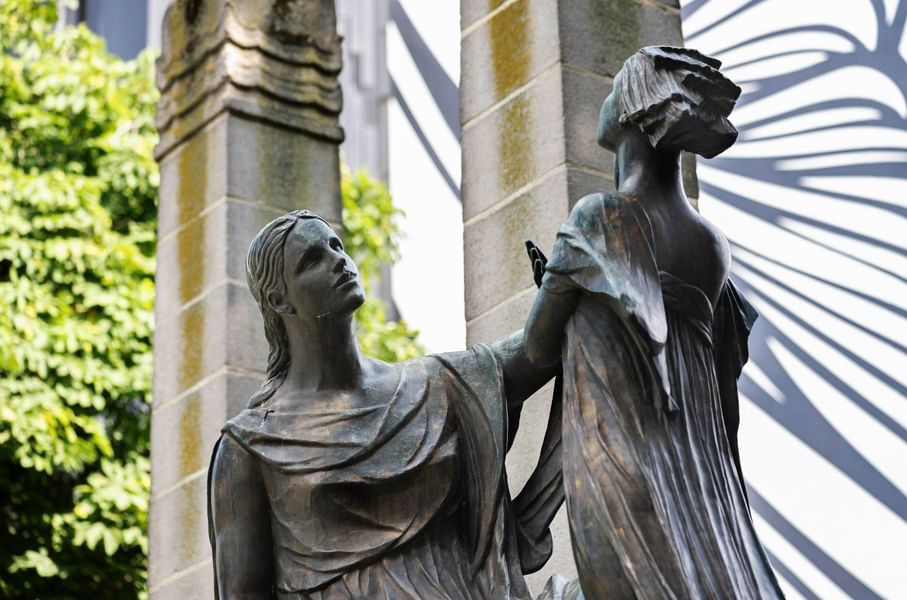 Statue en bronze d'une femme tenant une torche devant une façade architecturale à Hotel Barsey by Warwick Brussels Bruxelles