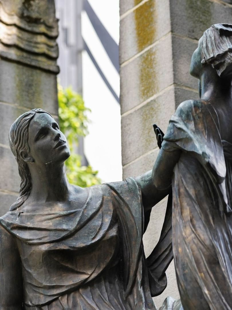 Bronze statue of two women in draped clothing beside stone pillars at Hotel Barsey by Warwick