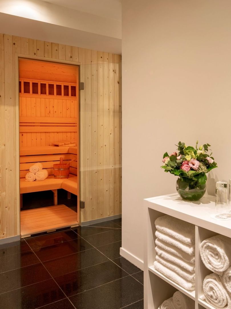 Sauna en bois avec bancs et étagère blanche avec serviettes et pommes vertes au Warwick Brussels Grand-Place