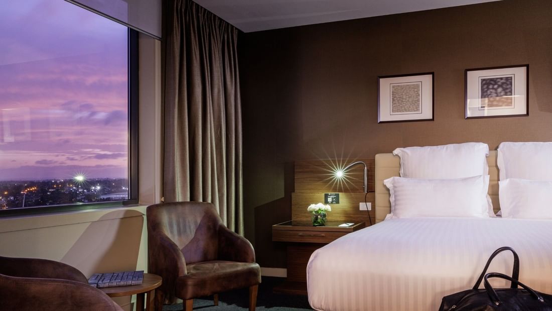 Stylish bedroom with large bed and chairs at Pullman Sydney Olympic Park.