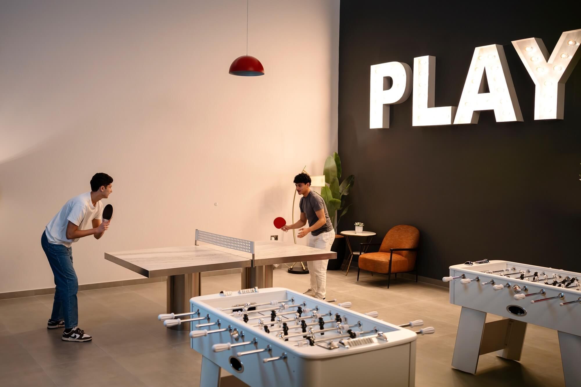 Two guests enjoy an exciting table tennis match at the stylish Level Up Gaming Hub inside DAMAC Maison Aykon City